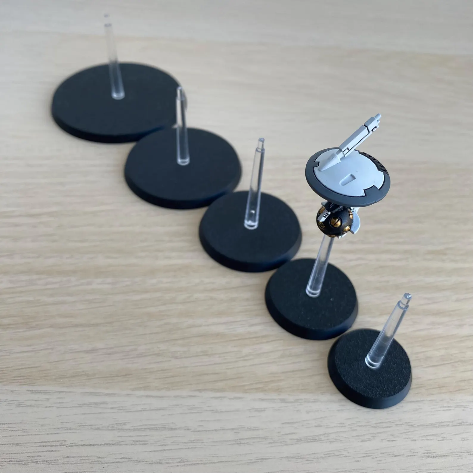 A selection of black, circular bases with clear plastic stems, designed for miniature figures.