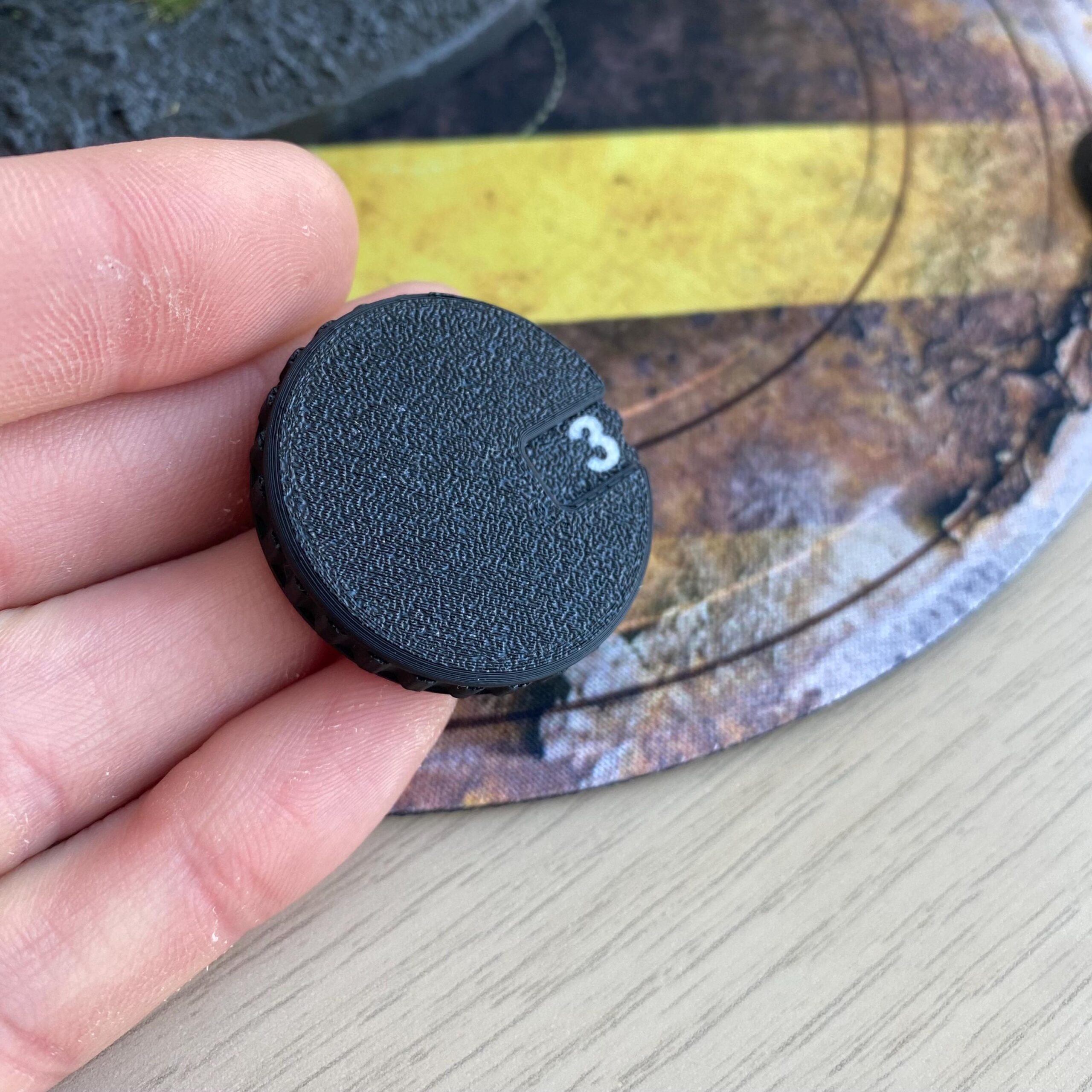 A circular black plastic dial with a textured surface and a grooved edge.