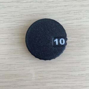 A circular black object with a textured surface and a small rectangular cutout on the right side.