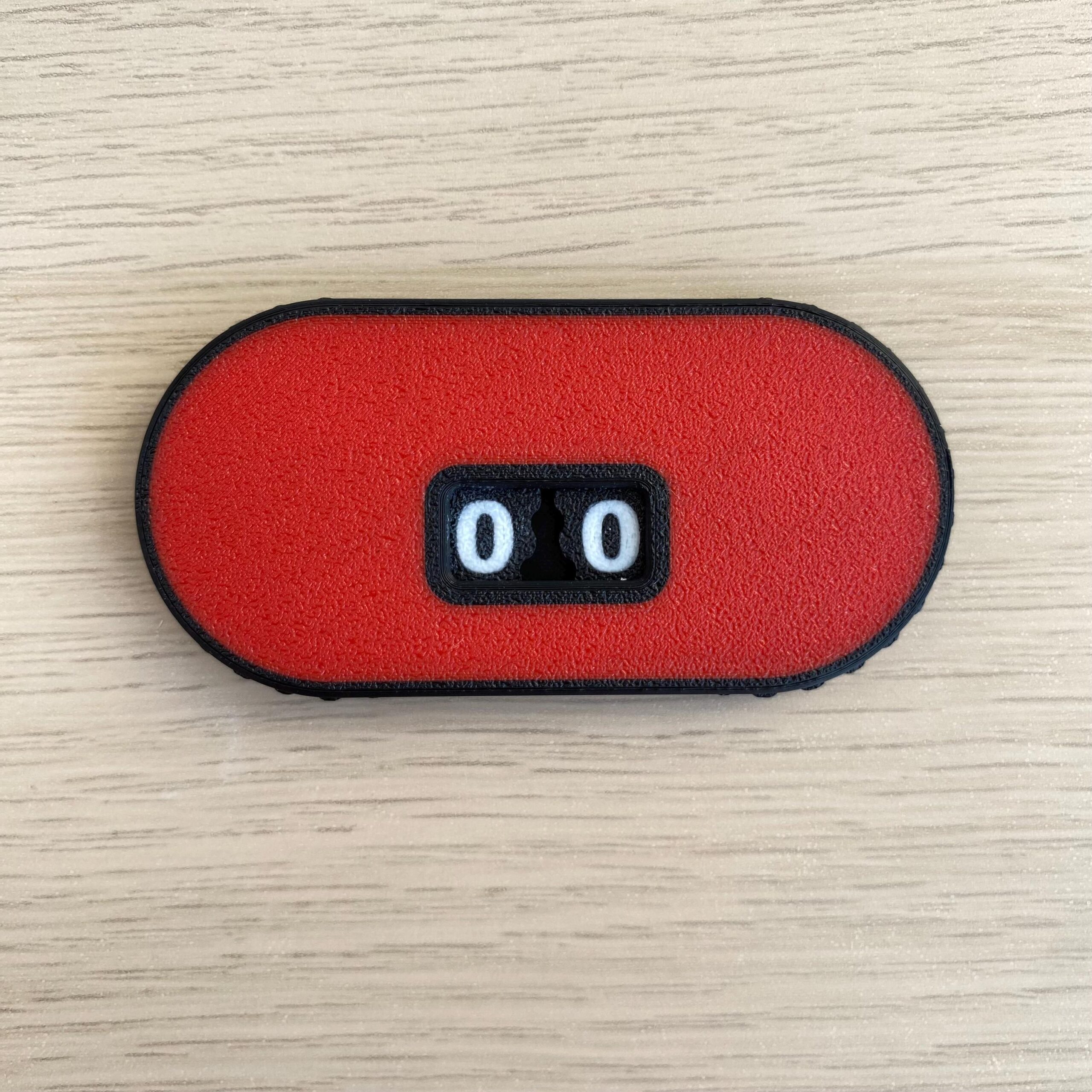 An oblong, red, textured counter device with a black border.