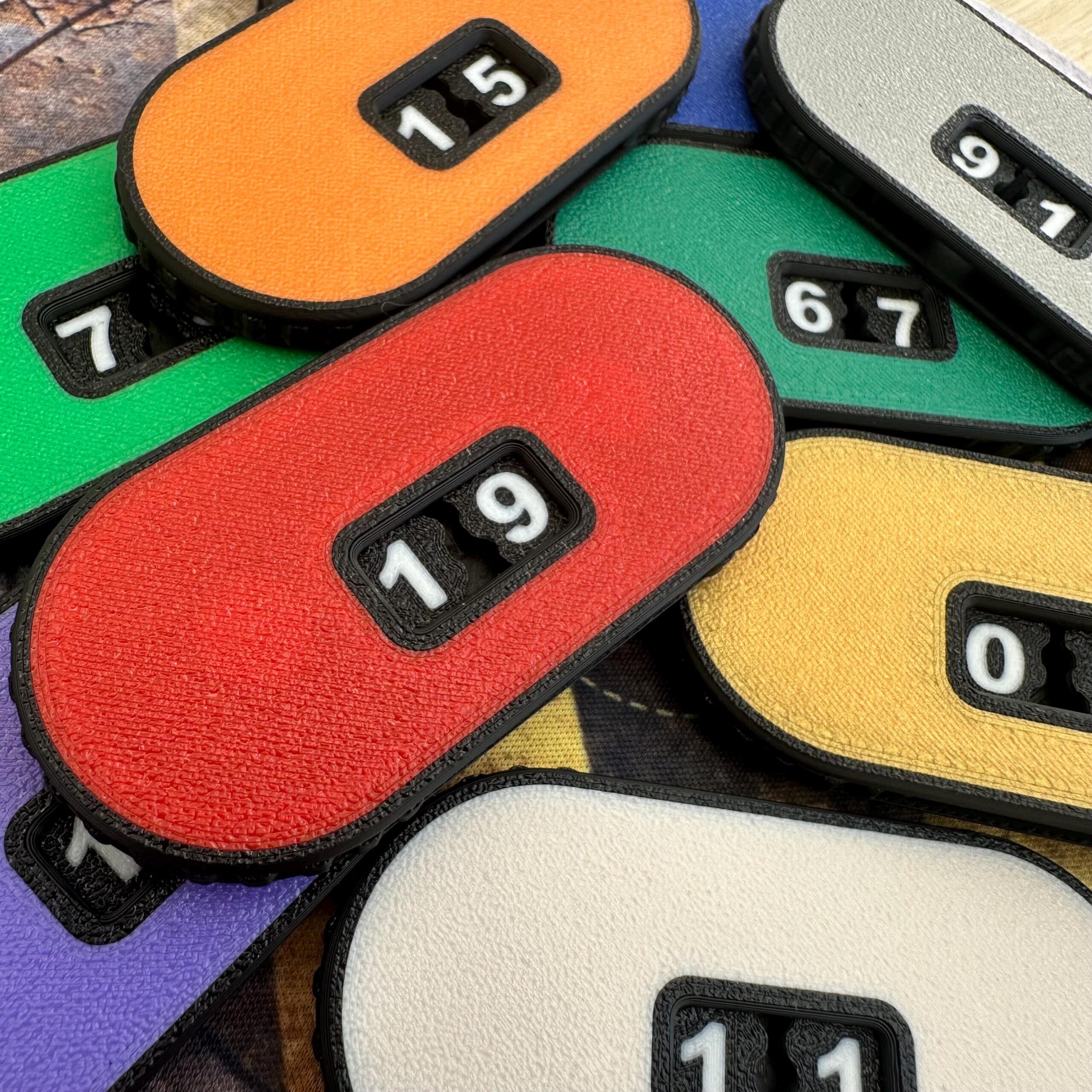 A collection of oval-shaped plastic counters in various colours including red, orange, yellow, green, purple, and white.