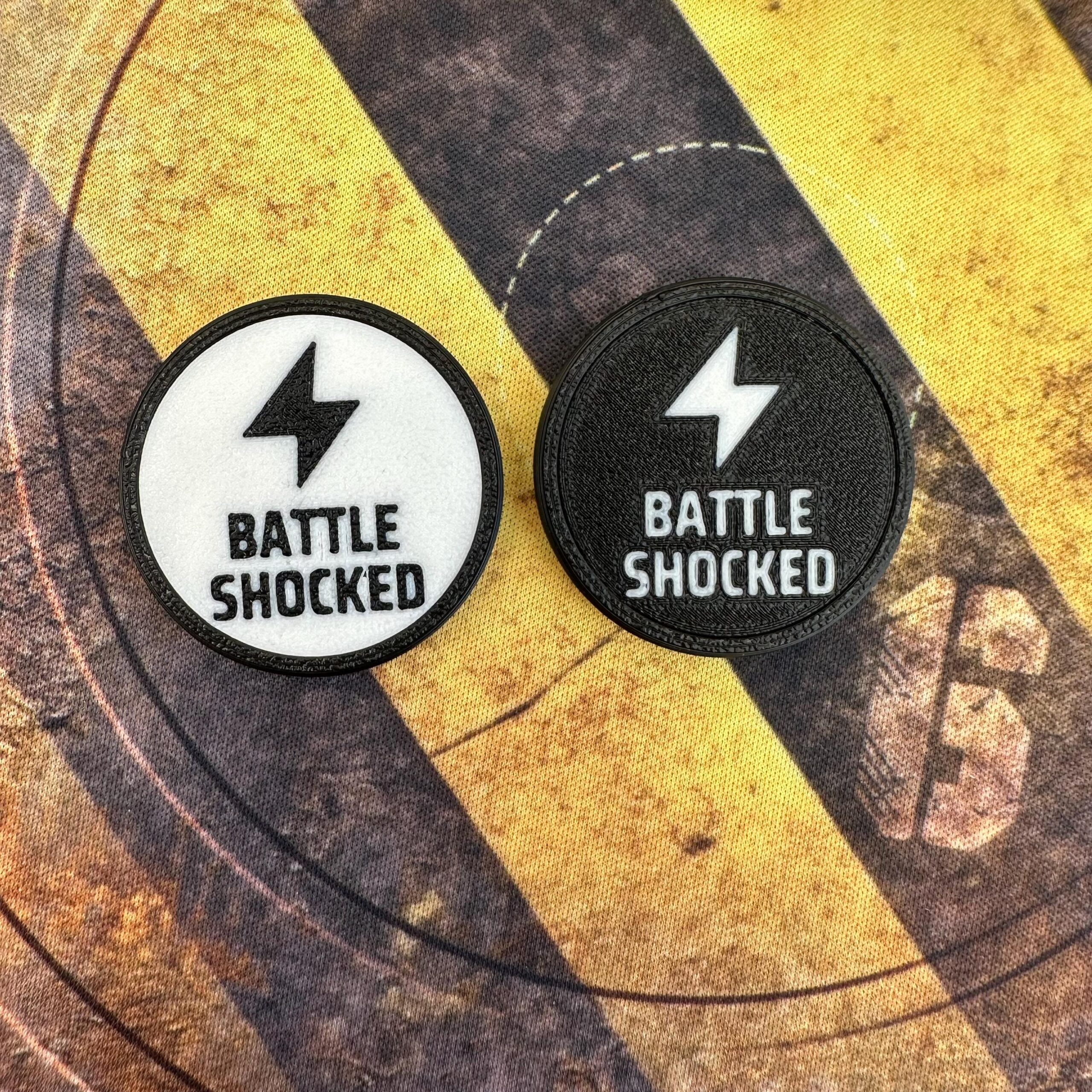 Two circular patches featuring a lightning bolt icon above the text BATTLE SHOCKED.