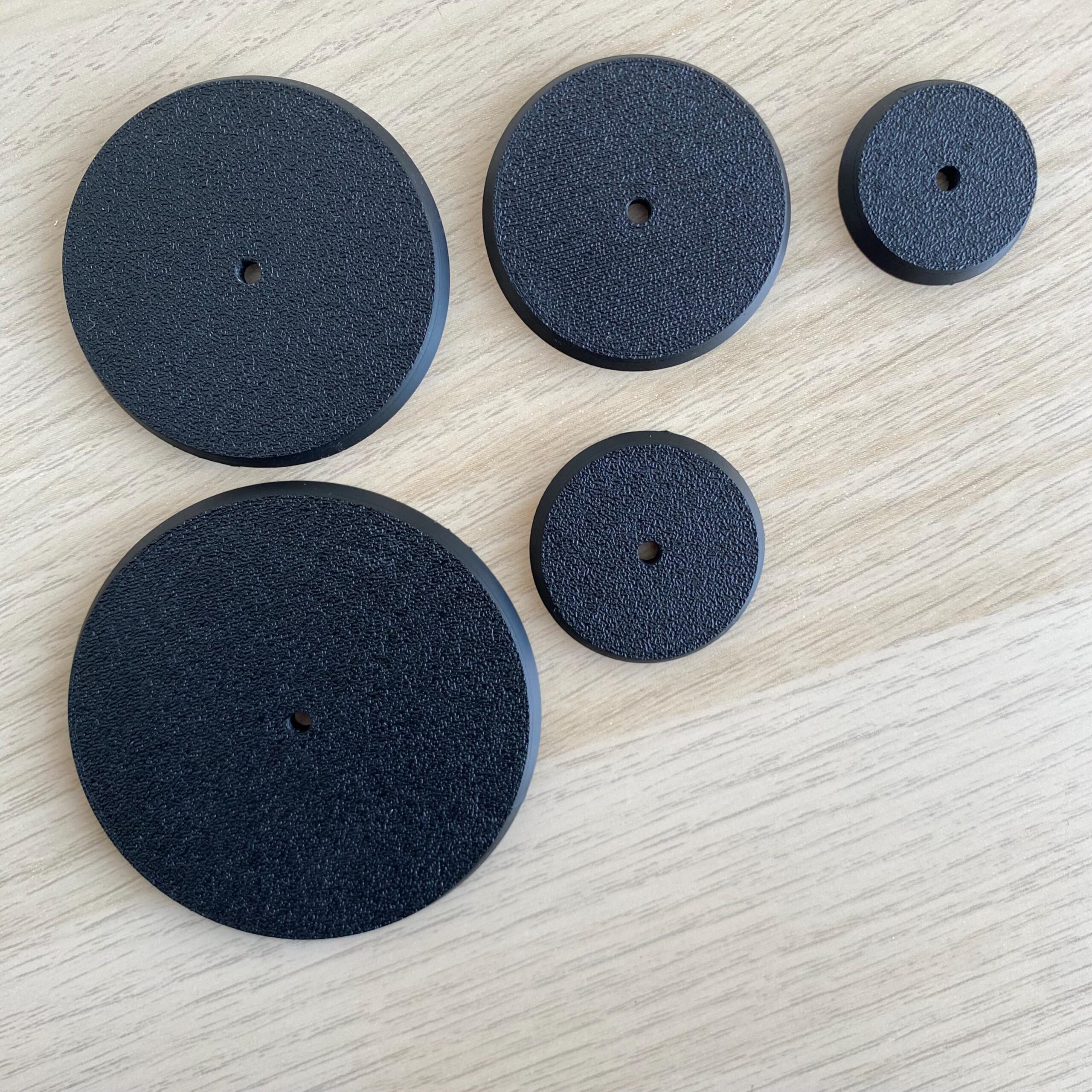 Five black, circular objects with a textured surface and a small hole in the centre.