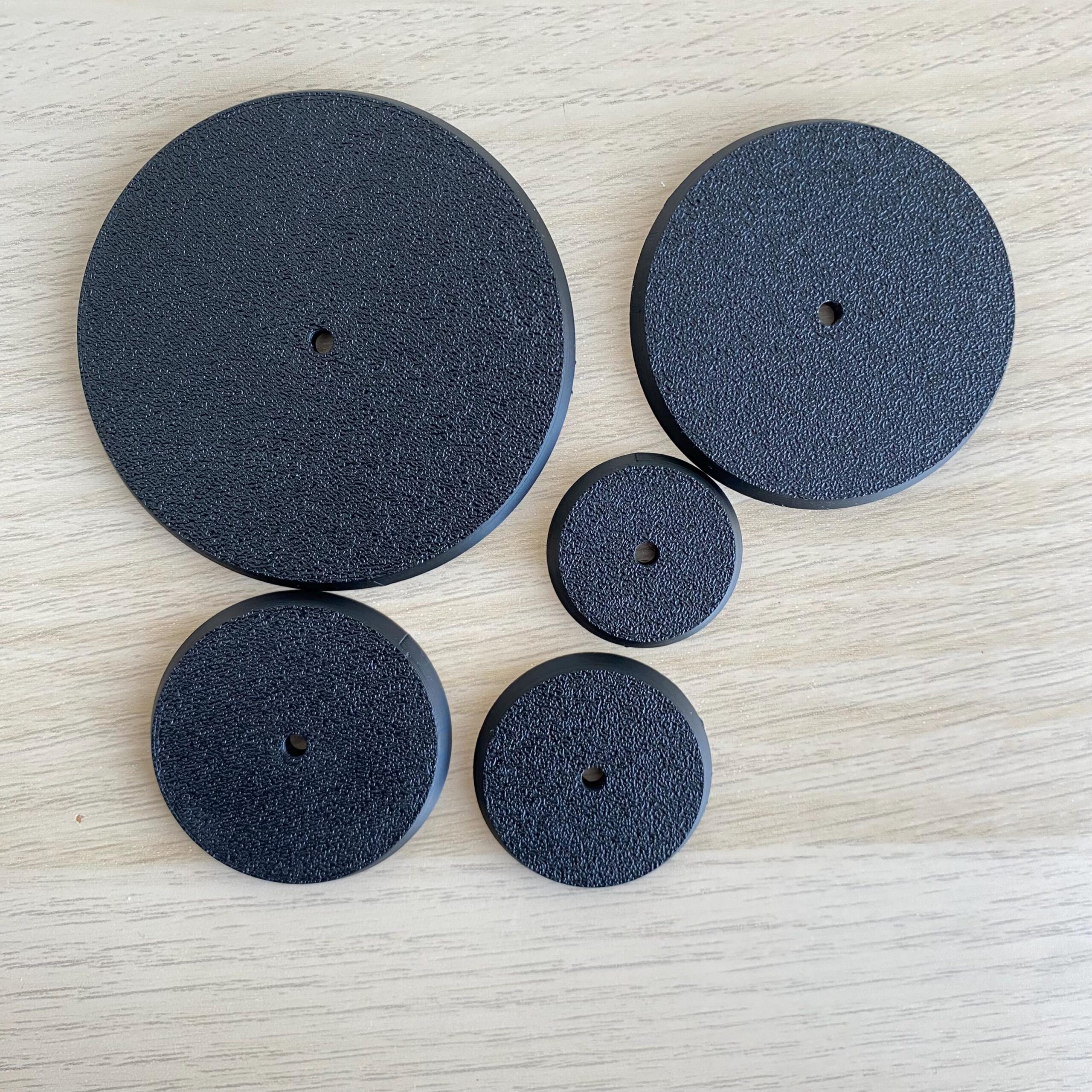 Six black, circular objects with a textured surface and a central hole.